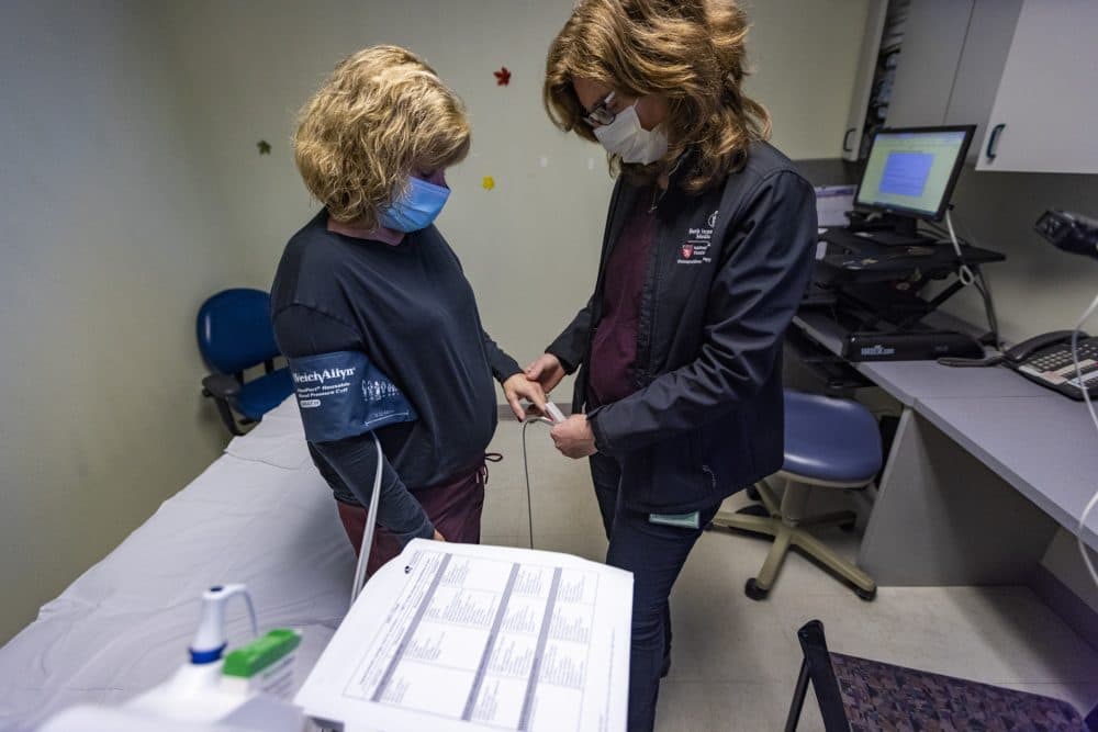 Physical therapist Heather Broglio places a pulse oximeter onto the finger of patient Holly Gochis. (Jesse Costa/WBUR)