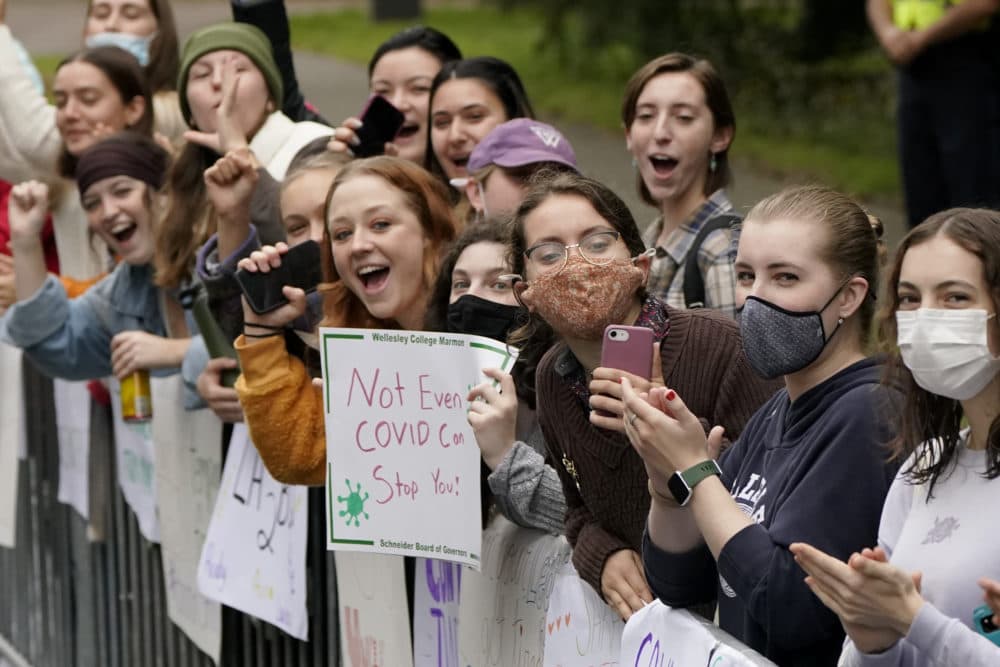 Women displays signs and cheer in front Wellesley College, in Wellesley, Mass., as a runner passes during the 125th Boston Marathon, Oct. 11, 2021. (Steven Senne/AP)