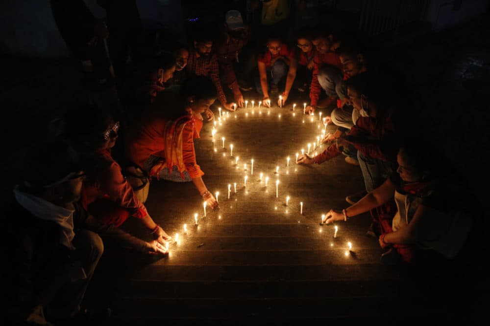 Members of a non-government organization make a red ribbon, the universal symbol of awareness and support for those living with HIV, with candles on the eve of World AIDS day in Ahmedabad, India, Tuesday, Nov. 30, 2021. (Ajit Solanki/AP)