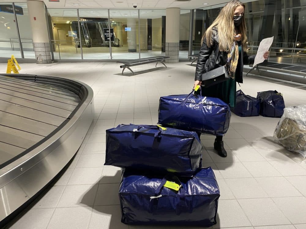 Megan Clark stands near a pile of bags at a luggage carousel at the Manchester, New Hampshire airport. (Sarah Gibson/NHPR)