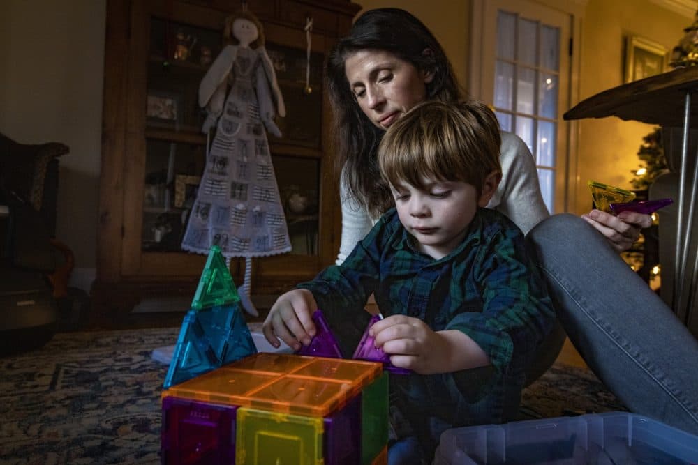 Sara Harold sits with her 3-year-old son, Finn, as he builds with magnetic tiles at their home. She struggled for more than a year to find special education services for her son, running into enrollment caps and programs that were short staffed. (Jesse Costa/WBUR)