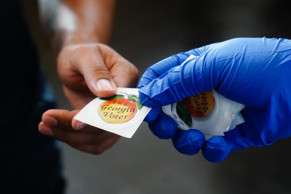 A man receives an &quot;I'm a Georgia Voter&quot; sticker after casting a ballot in Georgia's primary election on June 9, 2020, in Atlanta, Georgia. (Elijah Nouvelage/Getty Images)