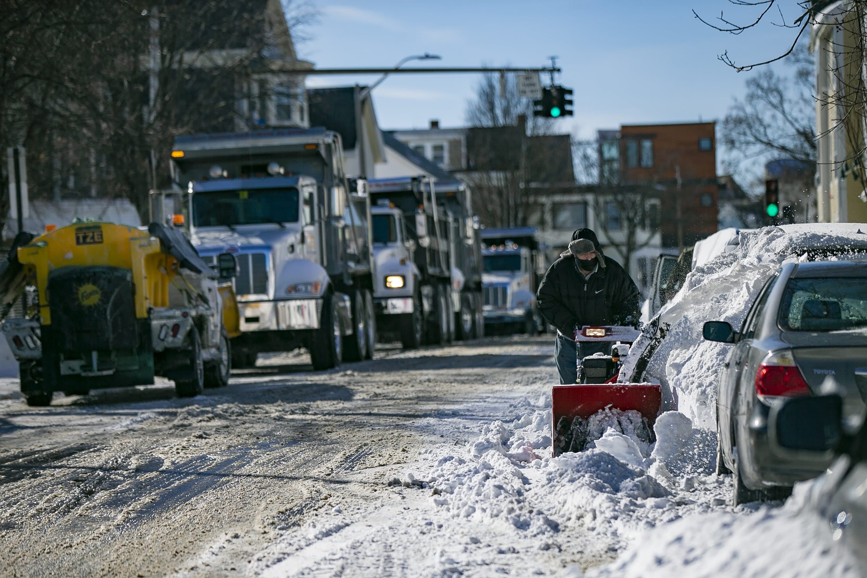 A man uses a snowblower to clear snow from in front of his car on Cross Street in Somerville. (Jesse Costa/WBUR)