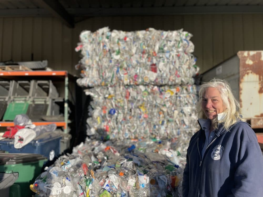 Denise Cumings, crew chief, stands in front of a bale of recycling at the Hooksett Transfer Station. (Mara Hoplamazian/NHPR)