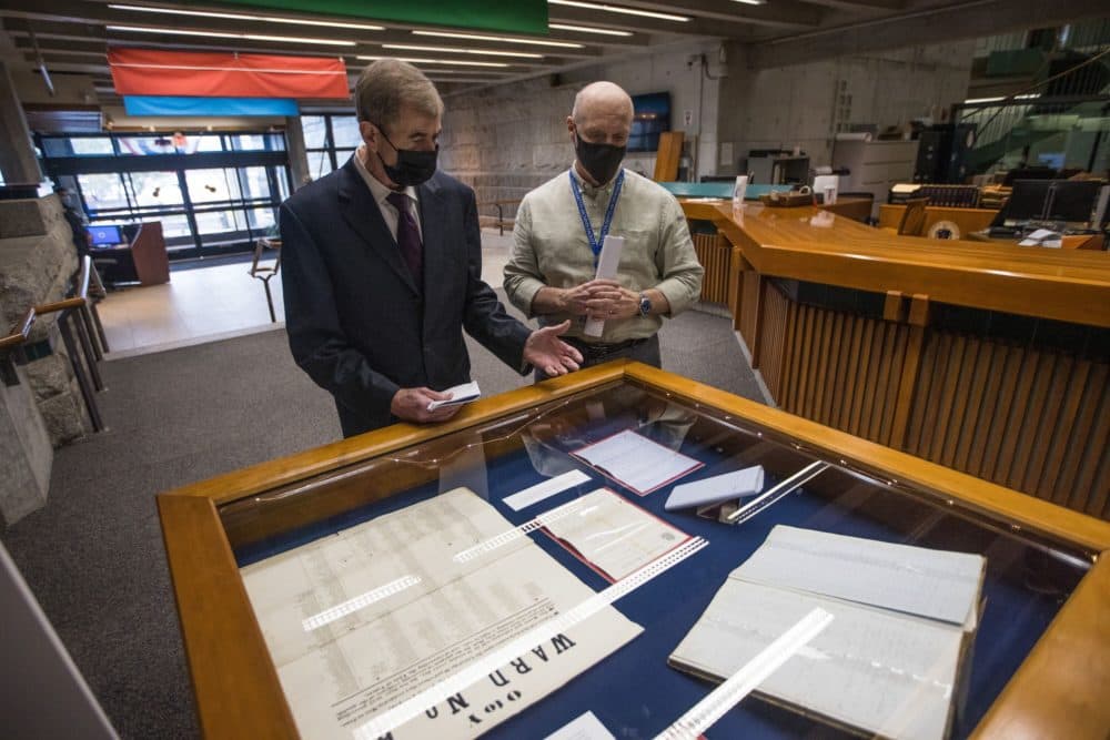 Secretary of State William Galvin and Michael Comeau, executive director of the Massachusetts Archives, review documents dating back from the 19th century pertaining to the expansion of the right to vote in Massachusetts. (Jesse Costa/WBUR)