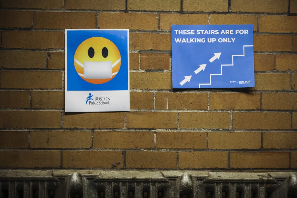 A sign reminding students to wear face masks and follow a set directional pattern are seen in the stairway of a Boston high school in February 2021. (Photo by Erin Clark/The Boston Globe via Getty Images)