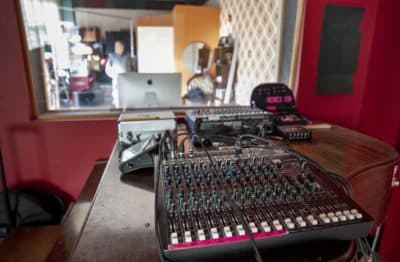 A mixing board sits on top of a piano in one of the studios at the Brighton Sound Museum. (Robin Lubbock/WBUR)
