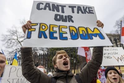 Artem Laptiev, an MIT student from Ukraine, chants and holds a sign during a rally to support Ukraine at the State House. (Jesse Costa/WBUR)