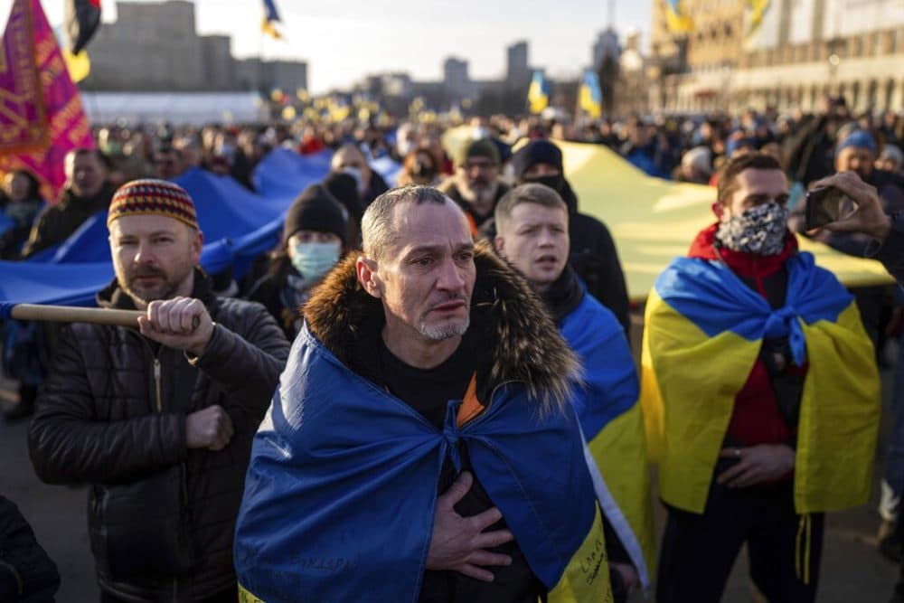 A demonstrator cries listening a national anthem as other rally with Ukrainian national flags in the center of Kharkiv, Ukraine's second-largest city, Saturday, Feb. 5, 2022. (Evgeniy Maloletka/AP Photo)