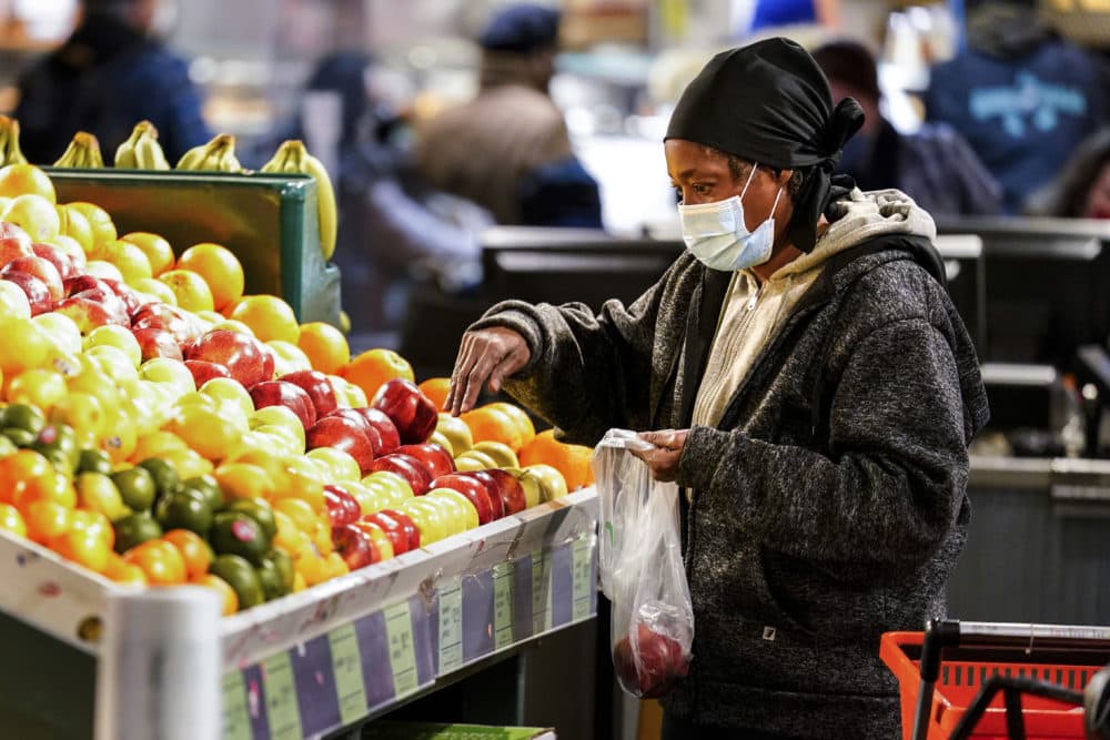 A shopper waring a proactive mask as a precaution against the spread of the coronavirus selects fruit at the Reading Terminal Market in Philadelphia, Wednesday, Feb. 16, 2022. (Matt Rourke/AP)