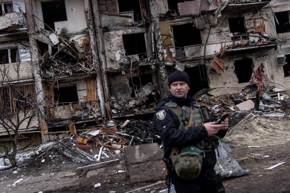 A Ukrainian police officer stands in front of a damaged residential block hit by an early morning missile strike on February 25, 2022 in Kyiv, Ukraine. (Chris McGrath/Getty Images)