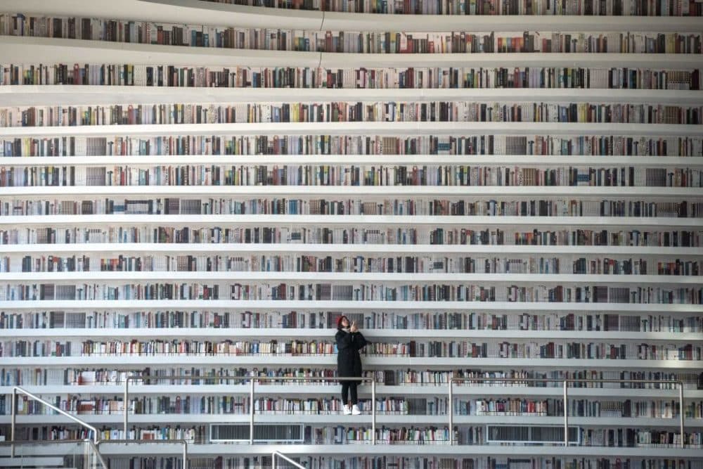 This picture taken on November 14, 2017 shows a woman taking pictures at the Tianjin Binhai Library,  a futuristic Chinese library has wowed book lovers around the world with its white, undulating shelves rising from floor to ceiling. (Fred Dufour/AFP via Getty Images)