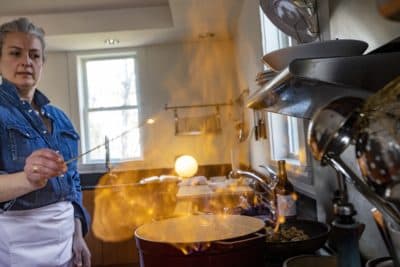 Food stylist Christine Tobin uses a long match to ignite cognac in the Dutch oven. (Jesse Costa/WBUR)