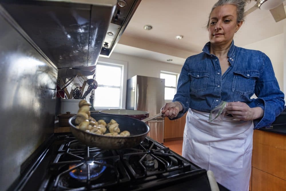 Christine Tobin tosses mushrooms and butter in a skillet preparing coq au vin, one of Julia Child’s signature dishes. (Jesse Costa/WBUR)
