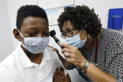 Dr. Janice Bacon, a primary care physician with Central Mississippi Health Services, gives Jeremiah Young, 11, a back-to-school physical, at the Community Health Care Center on the Tougaloo College campus, in Tougaloo, Miss., on Aug. 14, 2020.(Rogelio V. Solis/AP)