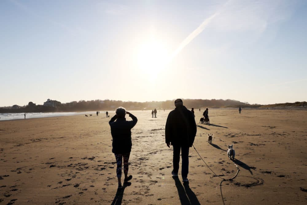 A woman shielded her eyes as she walked along Good Harbor Beach in Gloucester, Mass. on November 18, 2021. (Jessica Rinaldi/The Boston Globe via Getty Images)