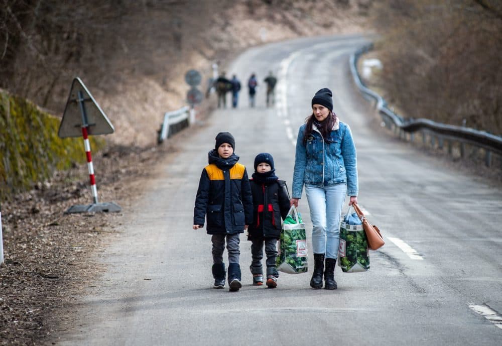 A woman with two children and carrying bags walk on a street to leave Ukraine after crossing the Slovak-Ukrainian border in Ubla, eastern Slovakia, close to the Ukrainian city of Welykyj Beresnyj, on Feb. 25, 2022, following Russia's invasion of the Ukraine. (Peter Lazar/AFP via Getty Images)