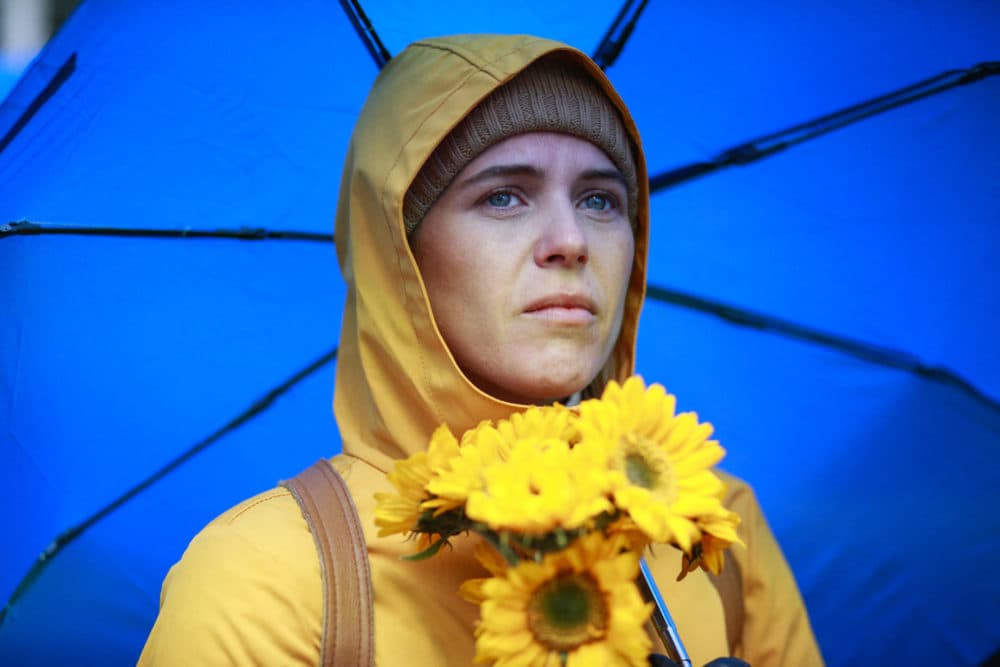 A woman holds a bouquet of flowers as demonstrators gather in support of Ukraine in Times Square, New York, on March 12, 2022. (Kena Betancur/AFP via Getty Images)
