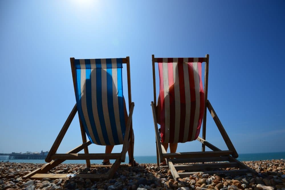 People relax in deck chairs on the beach. (Carl Court/AFP via Getty Images)