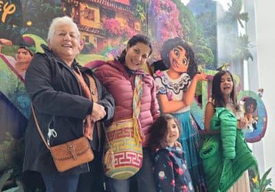 The author and her family pose in front of the &quot;Encanto&quot; movie poster. (Courtesy of Lorena Hernández Leonard)