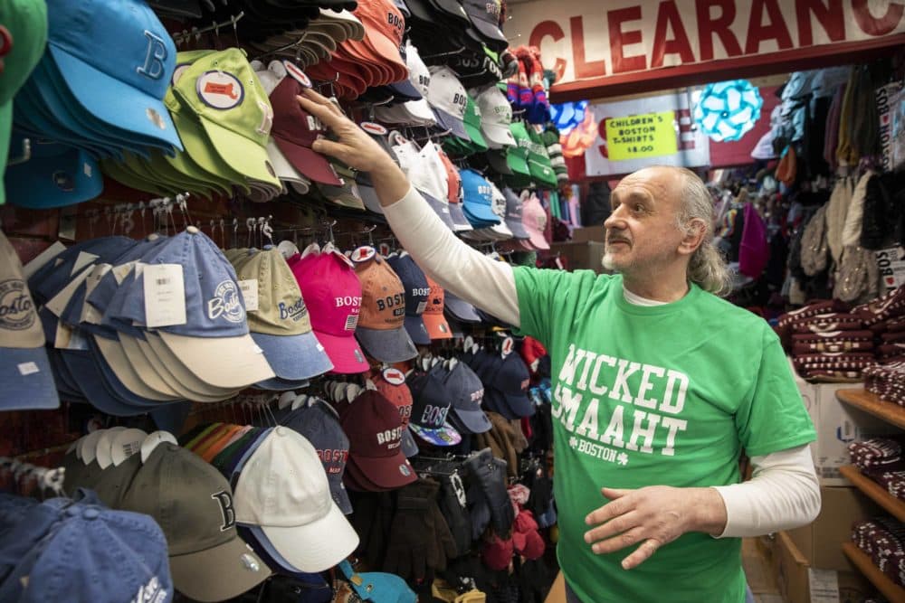 Karl Volker, the owner of the Underground Express souvenir store in downtown Boston, arranges the hats. (Robin Lubbock/WBUR)