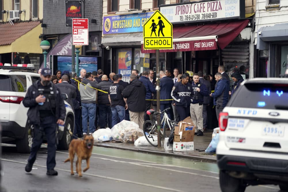 New York City Police Department personnel gather at the entrance to a subway stop in Brooklyn borough. (John Minchillo/AP)