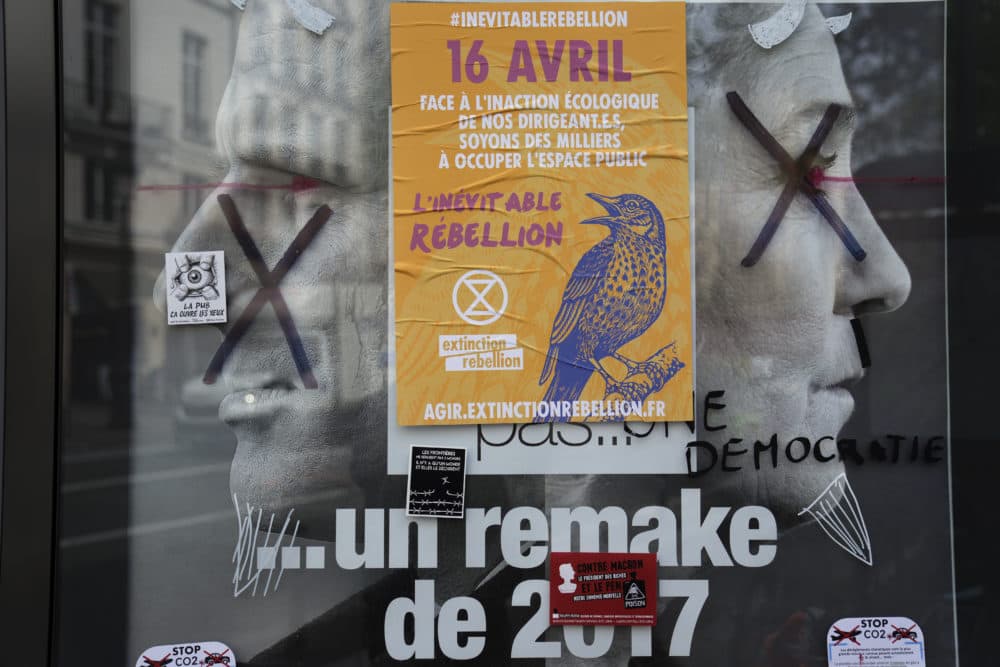 A torn front page ad shows incumbent President Emmanuel Macron and challenger Marine Le Pen as the environmental group Extinction Rebellion takes part in a three-day demonstration against what they call France's inaction on climate issues. French President Emmanuel Macron is in pole position to win reelection Sunday, April 24, 2022 in France's presidential runoff. (Francois Mori/AP)