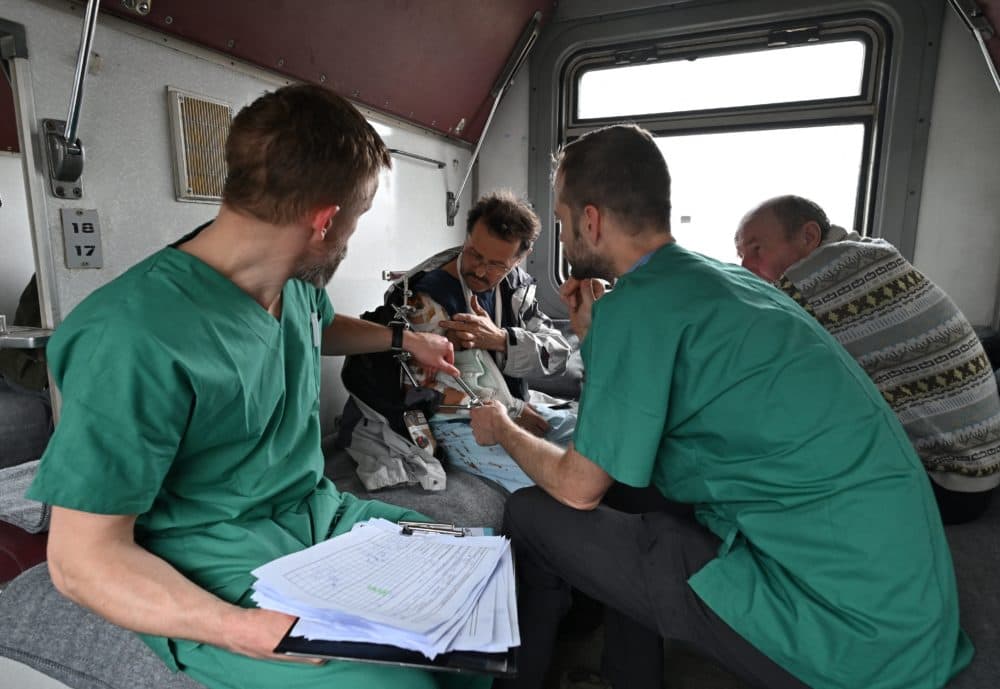 MSF doctors Stig Walravens (2nd R), 33, and Yaroslav (L), 39, care for Oleh, 58, a patient on a medical evacuation train on its way to the western Ukrainian city of Lviv on April 10, 2022. - (Genya Savilov/AFP via Getty Images)