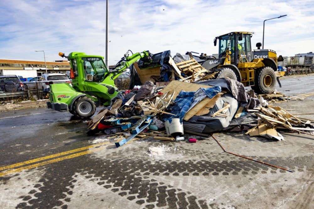 In this WBUR file photo, two construction trucks remove a pile of debris from the tent encampment near the so-called &quot;Mass. and Cass' area in January 2022. (Jesse Costa/WBUR)