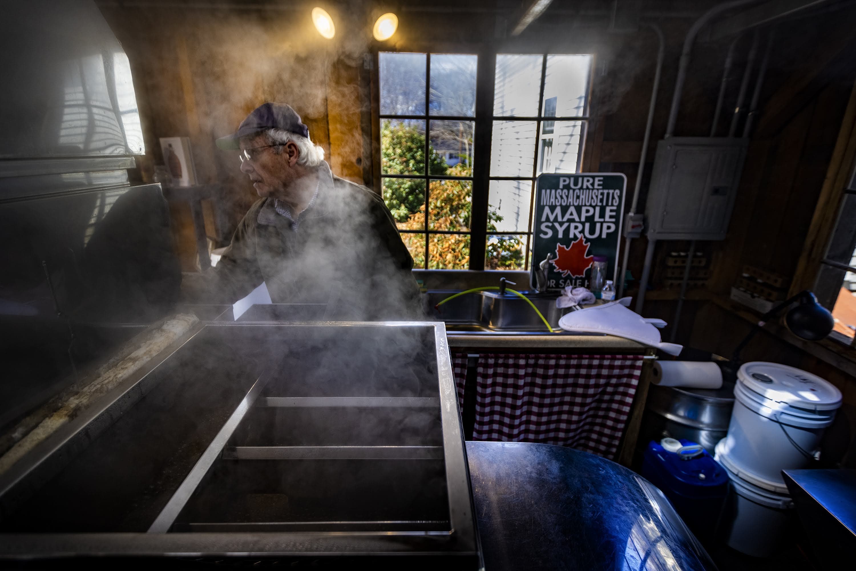 Ronald Kay checks the evaporator in the maple sugar shack at Maynard Maple to process sap he’s collected to make locally sourced maple syrup. (Jesse Costa/WBUR)