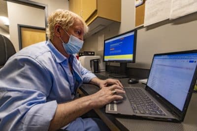 Between patient visits at AFC Urgent Care in Worcester, Dr. Frank Duggan sets up a telemedicine appointment through a platform that provides people in Ukraine with free medical assistance via a network of US and European physicians. (Jesse Costa/WBUR)