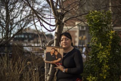 Ivett Marquez stands in the garden her father cared for next to a photo of him with his wife and Ivett's mother, Irma, outside their home in Brooklyn. Marquez died from COVID on April 8, 2020 during one of the deadliest weeks in New York City. (David Goldman/AP)