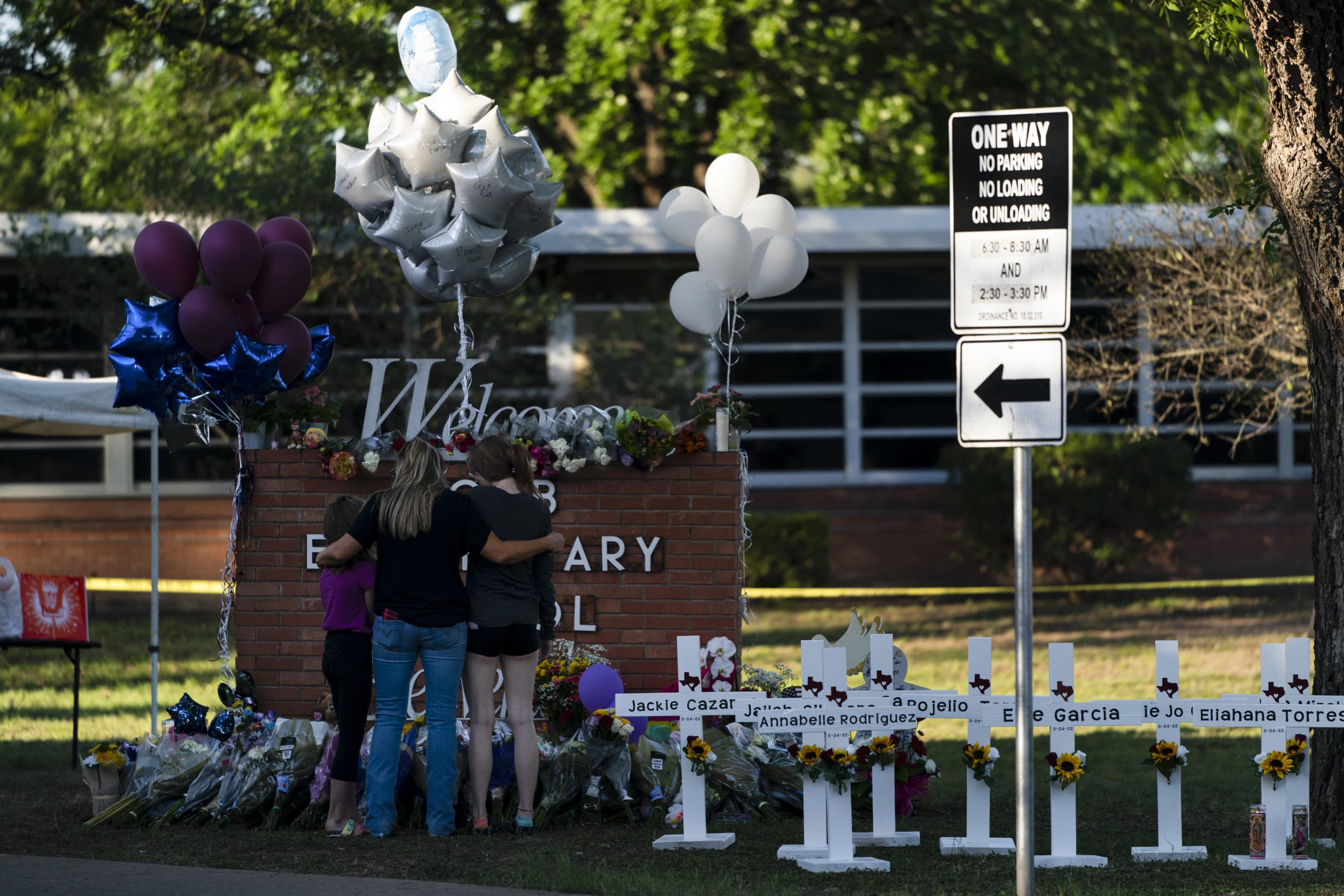A family pays their respects next to crosses bearing the names of Tuesday's shooting victims at Robb Elementary School in Uvalde, Texas, Thursday, May 26, 2022. (Jae C. Hong/AP)