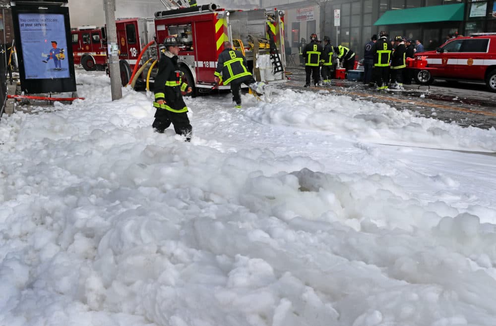 Firefighters walk through foam used to extinguish a four-alarm fire on Washington Street in the Dorchester in 2018. (David L. Ryan/The Boston Globe via Getty Images)