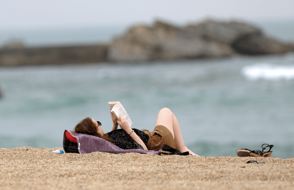 A woman reads a book on the beach (Iroz Gaizka/AFP via Getty Images)