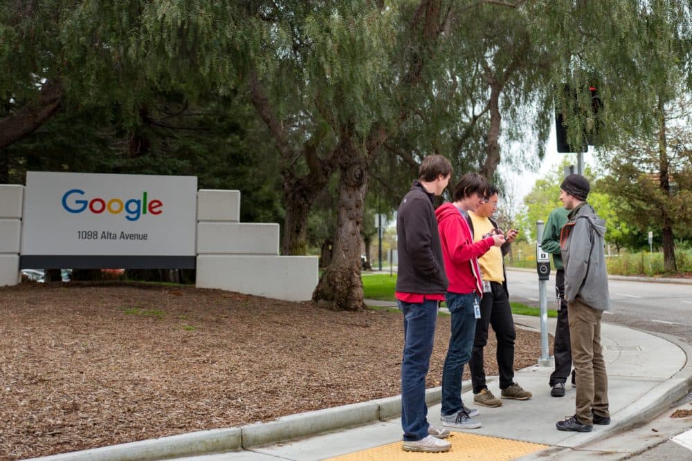 Technology workers stand in a group near signage for Google Inc at the Googleplex, the Silicon Valley headquarters of search engine and technology company Google Inc, Mountain View, California, April 7, 2017. (Smith Collection/Gado/Getty Images).