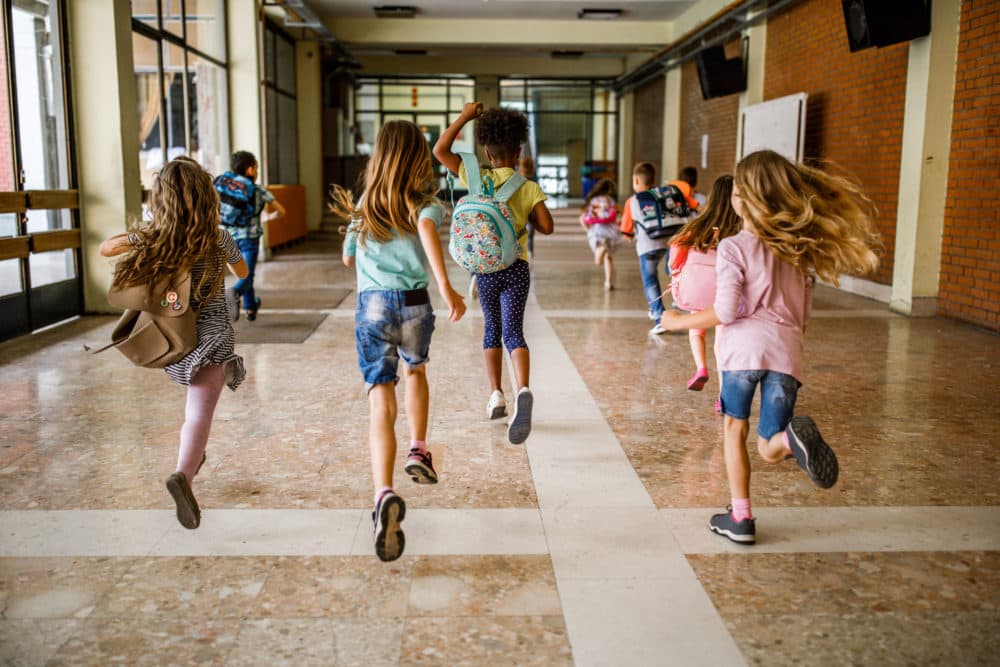 Elementary students run in a school hallway. (Getty)