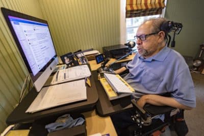 Charlie Carr uses a mouth wand to control a trackball connected to his computer. (Jesse Costa/WBUR)