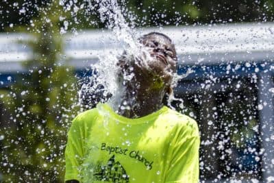 A young boy plays at the Rings Fountain at the Greenway on a very hot day. (Jesse Costa/WBUR)