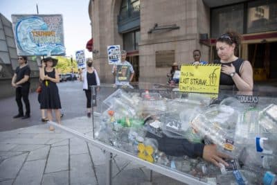 Staci Rubin mourns by the coffin of &quot;Death by Plastic&quot; at South Station, by artist Anne-Katrin Spiess. (Robin Lubbock/WBUR)