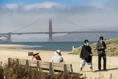 People wear face masks while strolling at Crissy Field East Beach in San Francisco (Noah Berger/AP)