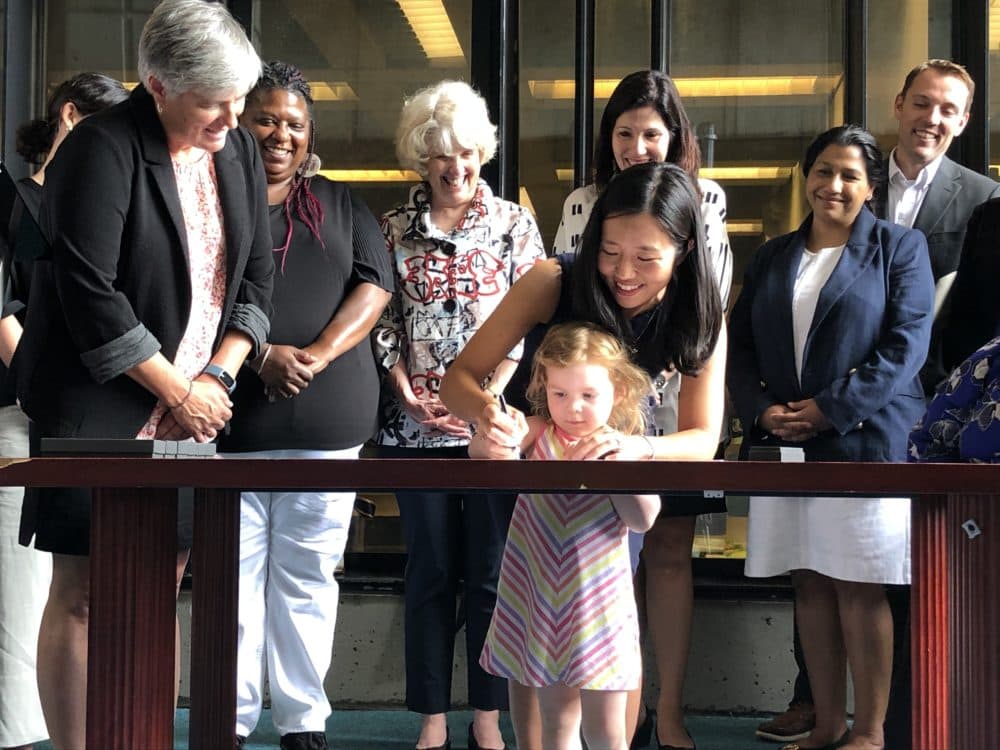 Mayor Michelle Wu signs an executive order clarifying how much office developers should pay for off-site child care. (Carrie Jung/WBUR)