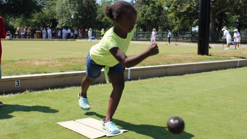 A young South End resident plays a game of lawn bowling at Hazelwood Park's newly reopened greens. (Ben Berke/The Public's Radio)