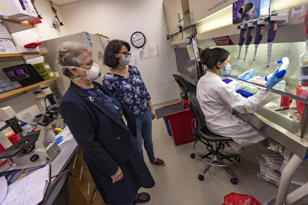 Dr. Liisa Selin and Anna Gil watch as research technician Taeva Cohen prepares blood samples for analysis in the pathology lab at the UMass Chan Medical School. (Jesse Costa/WBUR)