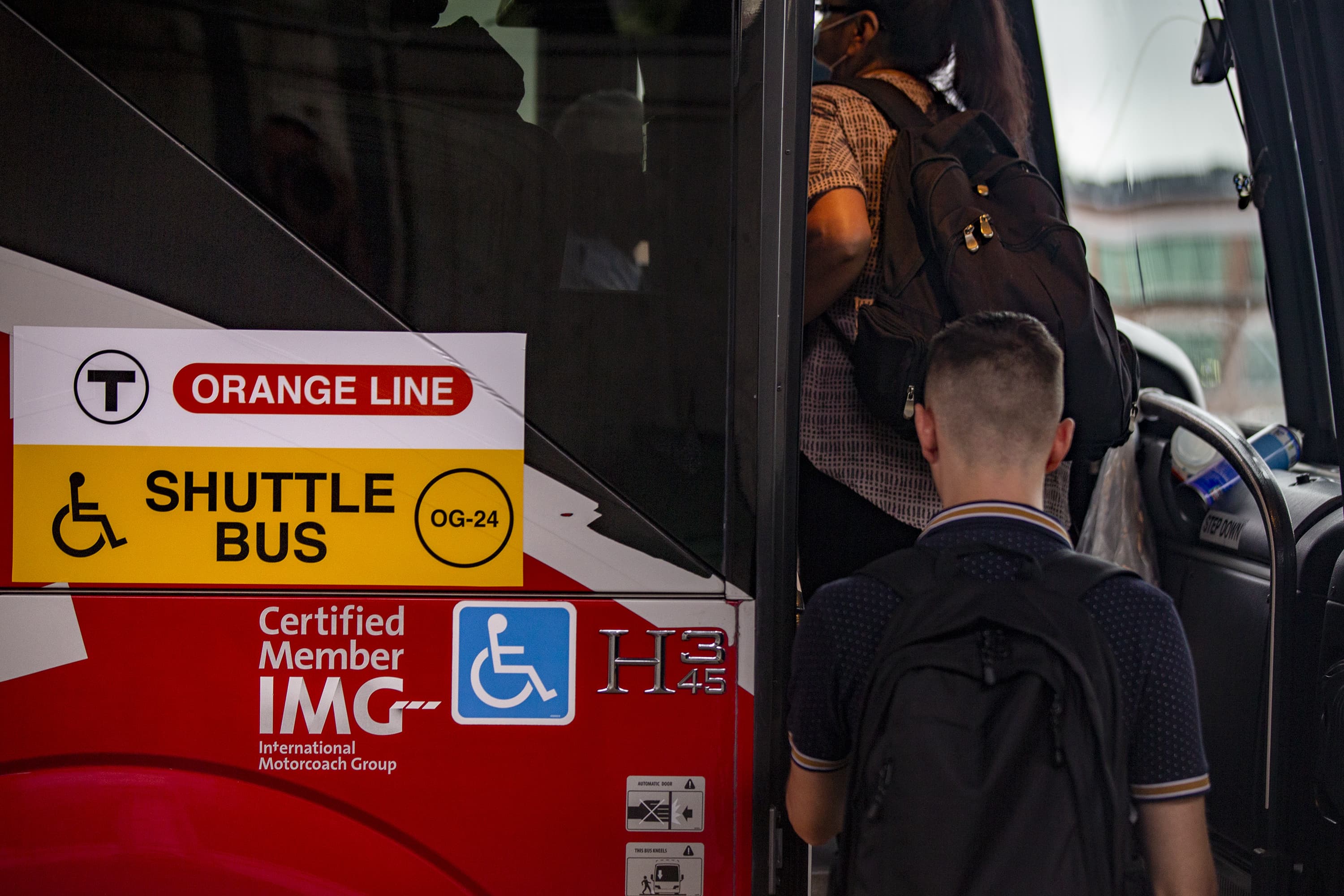 Early Monday morning commuters board an Orange Line shuttle bus at Sullivan Station. (Jesse Costa/WBUR)