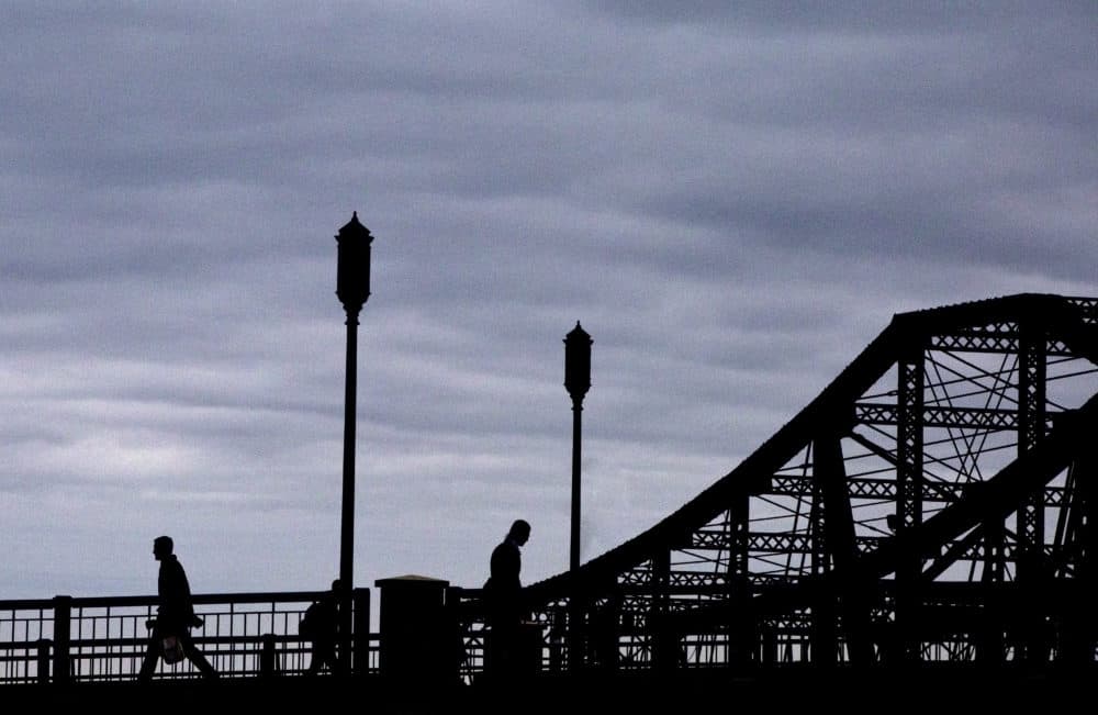 Pedestrians cross the Moakley Bridge as clouds hang over the skyline in Boston's Seaport district on Feb. 3, 2016. (Keith Bedford/The Boston Globe via Getty Images)