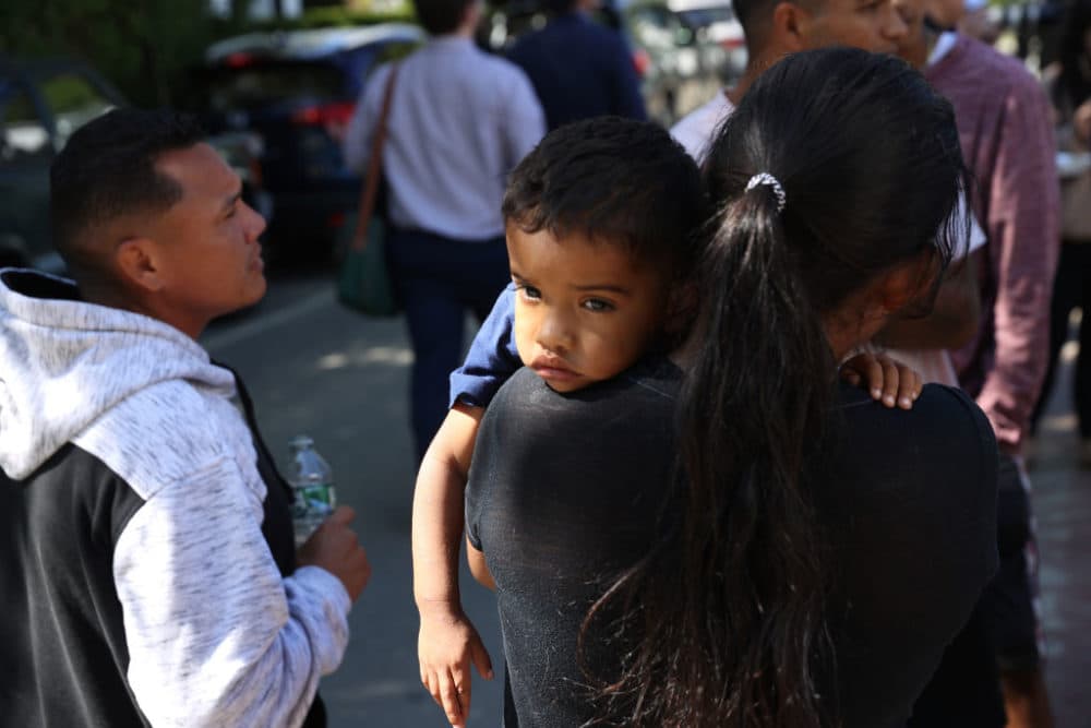 A mother and child spent some time outside the St. Andrew's Parrish House where migrants were being fed lunch with donated food from the community. (Jonathan Wiggs/The Boston Globe via Getty Images)
