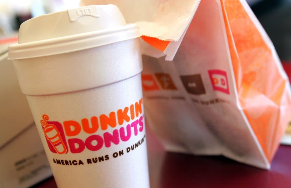 A cup of Dunkin' Donuts coffee and a donut bag sit on a counter. (Photo by Tim Boyle/Getty Images)