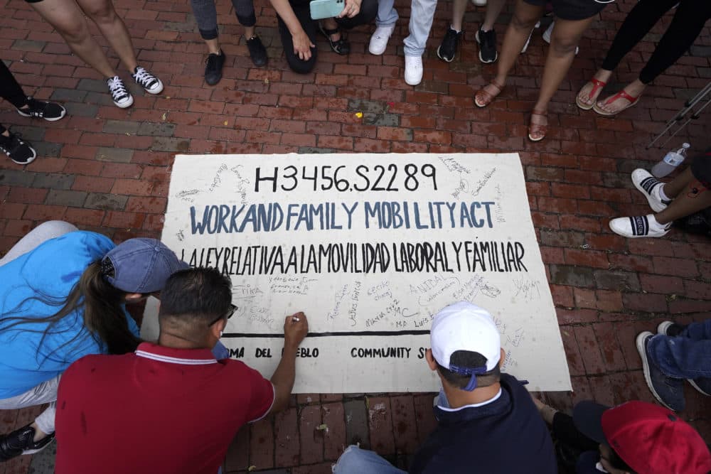People sign a banner during a rally in front of the State House in Boston on June 9 held in support of allowing immigrants in the country illegally to obtain driver's licenses in Massachusetts. (Steven Senne/AP)