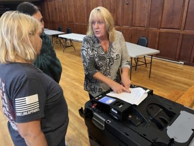 Brockton Elections Executive Director Cynthia Scrivani demonstrates for poll workers the proper way to set up a ballot box ahead of this fall's election. (Steve Brown/WBUR)